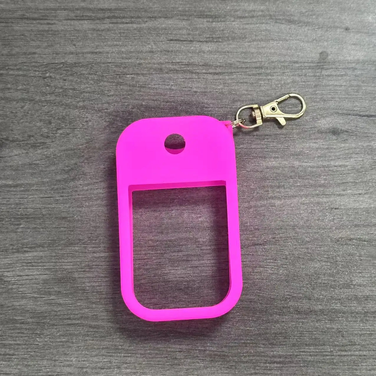 A bright pink silicone protective case for a hand sanitizer spray attached to a metal keyring.