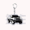 A silver metal key ring attached to a black off-road truck charm.