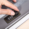 A hand is operating a hidden book safe with a combination lock on a gray surface.