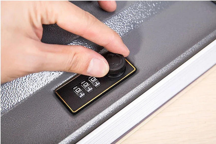 A hand is operating a hidden book safe with a combination lock on a gray surface.