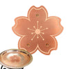 A copper disk with a floral design and multiple support points is shown next to a shallow, round metal dish.