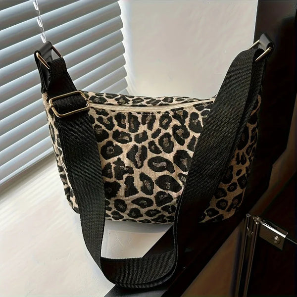 A black and beige leopard print nylon crossbody bag hanging against a light background.
