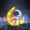 A LEGO astronaut figure shaped like a crescent moon, glowing gold, standing on a dark terrain under a starry night sky.