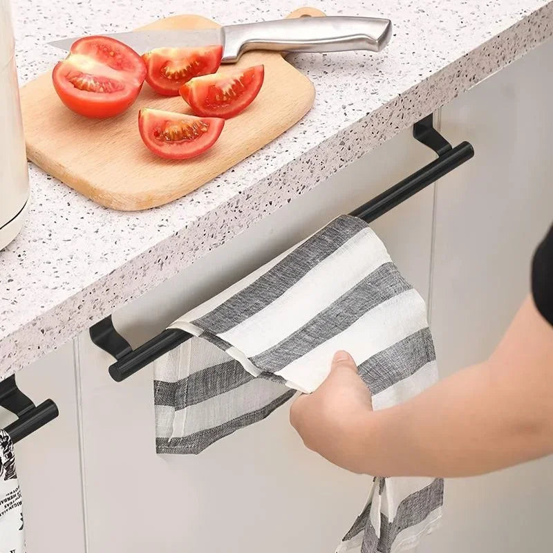 A hand is hanging a striped towel over a black over-cabinet towel rack mounted under a kitchen counter.