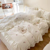 White duvet cover set with rose embroidery and lace details on a bed