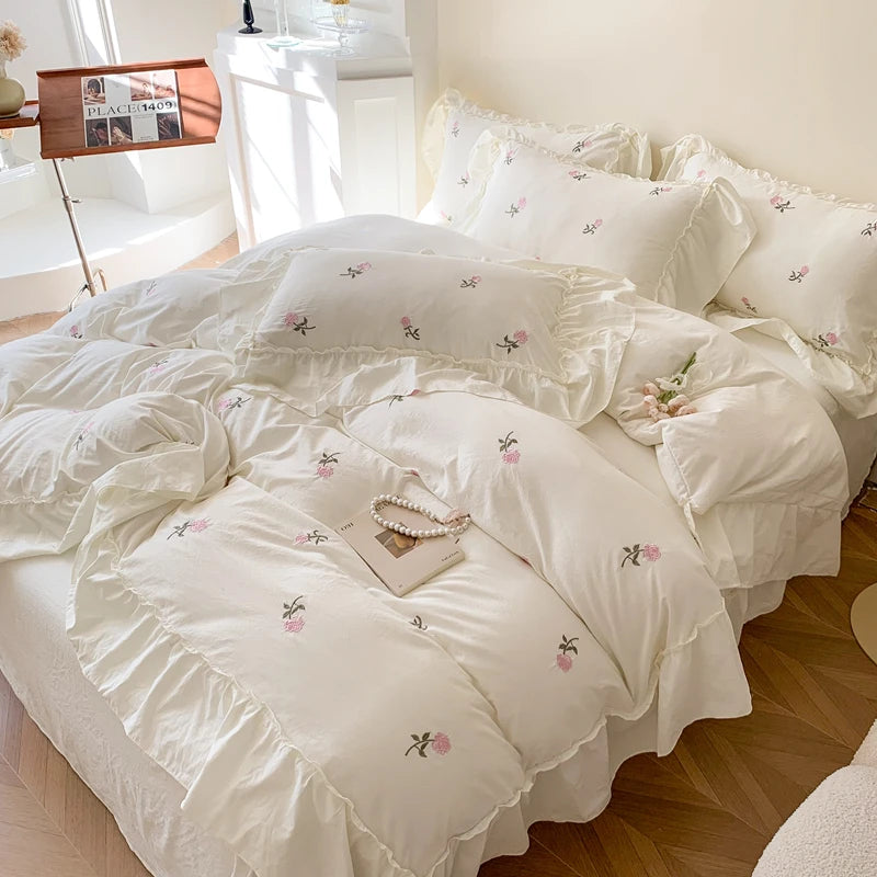 White duvet cover set with rose embroidery and lace details on a bed