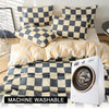 A white washing machine is shown next to a checkered print bedding set featuring gray and beige squares.