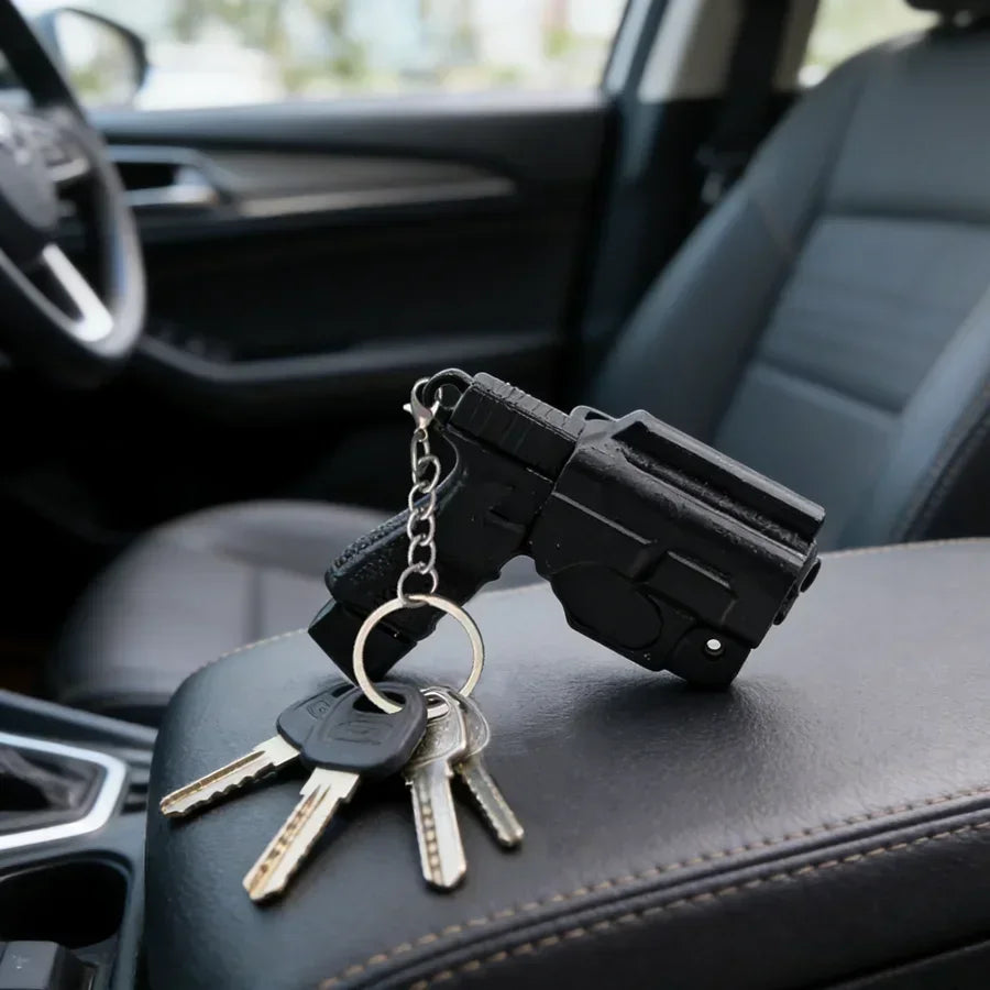 A black pistol-shaped keychain set with multiple keys rests on a dark car seat.