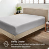 Una sábana ajustada de color gris claro sobre un marco de cama de madera con fondo de pared blanca.