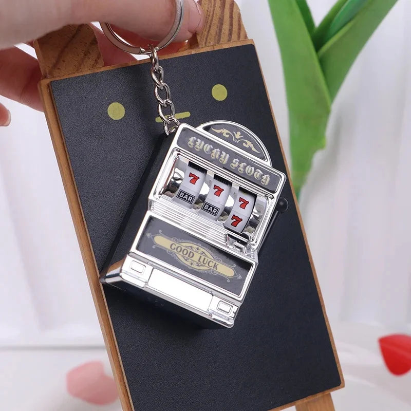 A silver mini fruit slot machine keychain fidget toy attached to a wooden board.