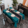 A long dining table set with a teal tablecloth, gold accents, and gray chairs in a modern interior.