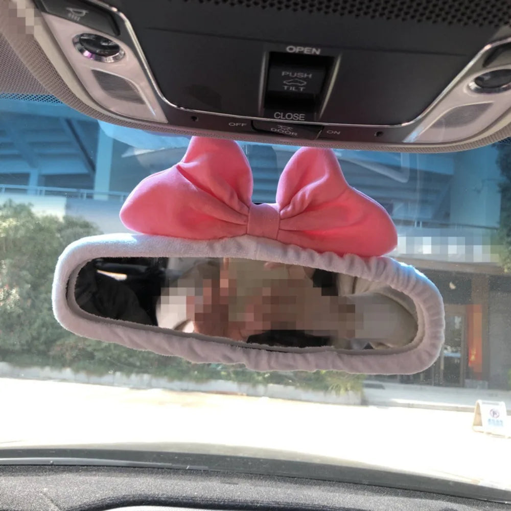 Pink bow shaped plush bear and pig car rearview mirror covers inside a vehicle