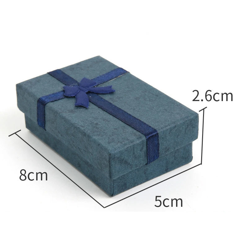 A rectangular dark blue velvet jewelry gift box tied with a navy ribbon, shown from above.