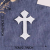 A white embroidered cross patch is shown against a dark blue denim fabric background.