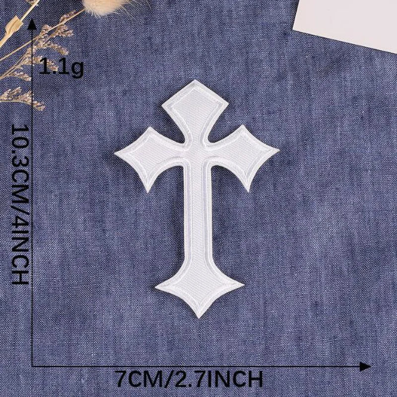 A white embroidered cross patch is shown against a dark blue denim fabric background.