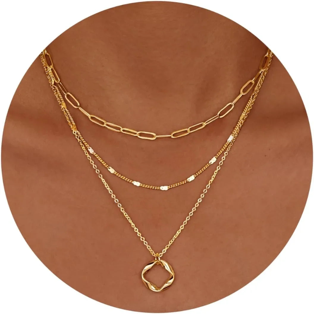 A layered necklace set featuring gold and silver chains displayed against a brown background.