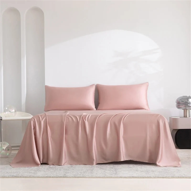 Luxuriöses Bambusbettlaken-Set in pudriger Rosatönung, drapiert auf einem Bett mit weißen Wänden.