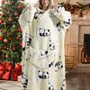 A woman models a cream-colored oversized wearable blanket hoodie with black panda print on a white background.