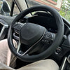 Interior view of a car showing a black steering wheel with leather cover and controls.