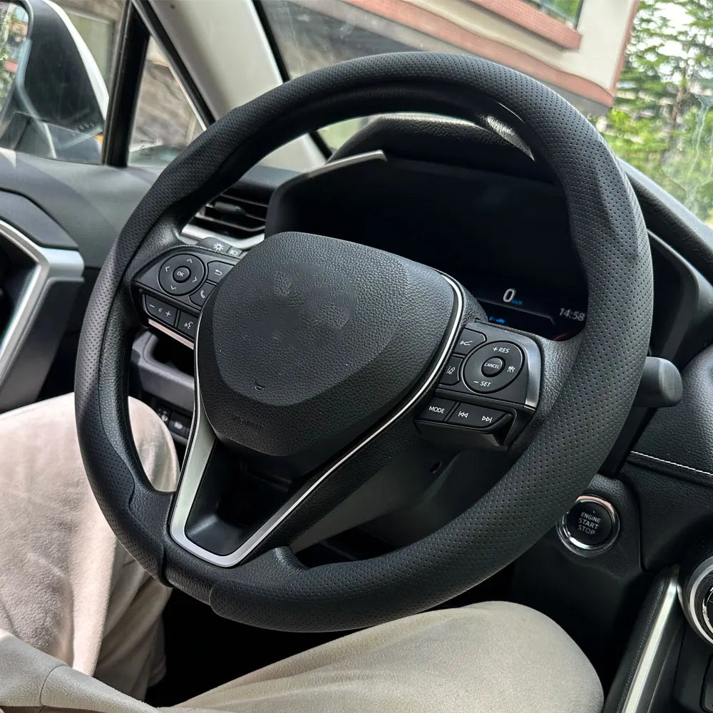 Interior view of a car showing a black steering wheel with leather cover and controls.