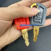A hand holds a set of replacement ignition keys for Caterpillar excavators, including a key and a lock.