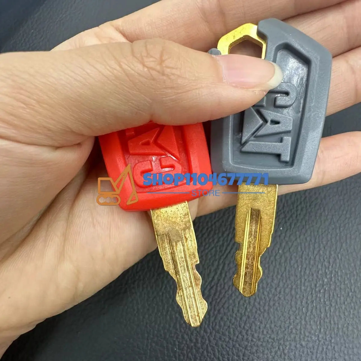 A hand holds a set of replacement ignition keys for Caterpillar excavators, including a key and a lock.