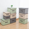 A set of stacked fabric storage boxes in shades of green and gray on a wooden floor.