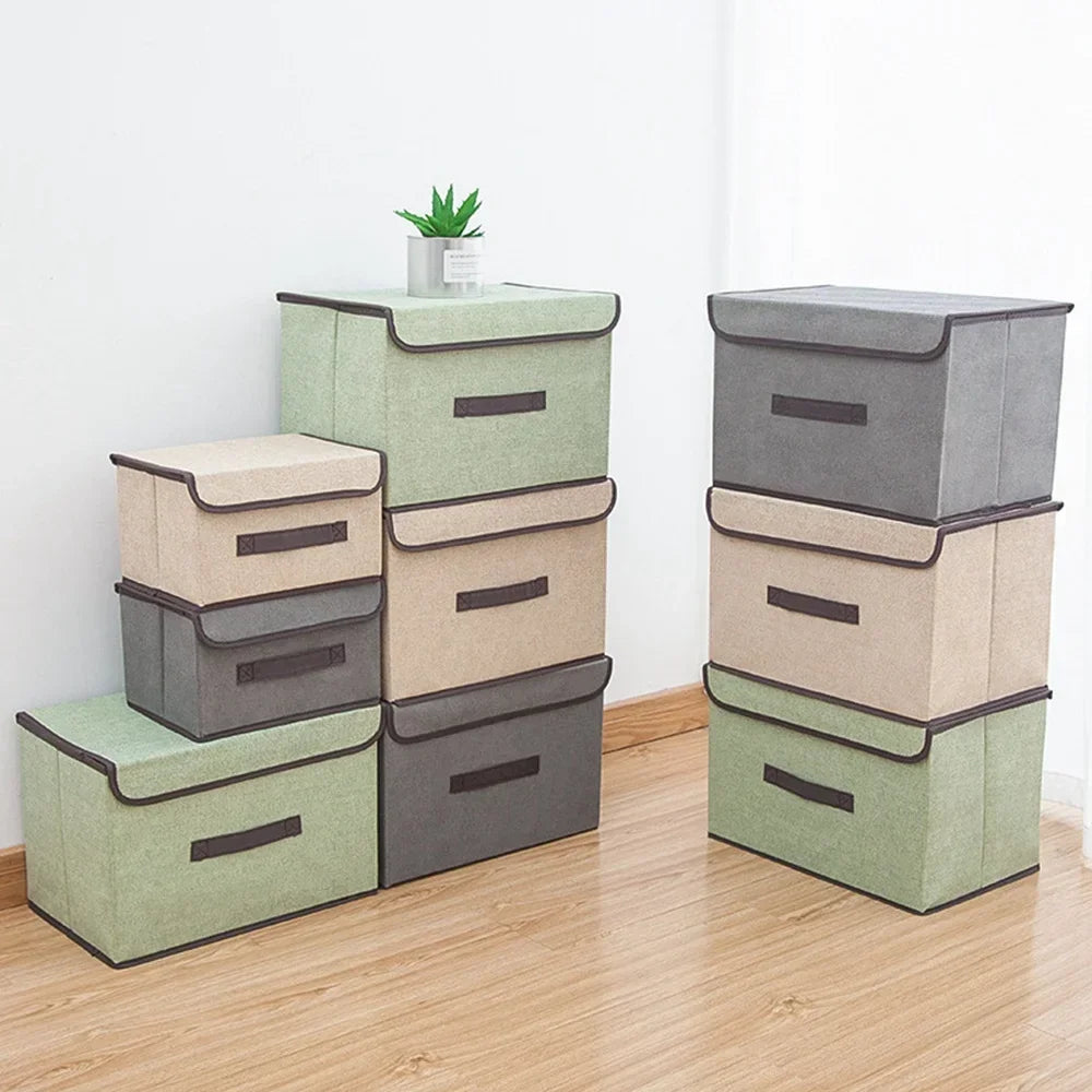 A set of stacked fabric storage boxes in shades of green and gray on a wooden floor.