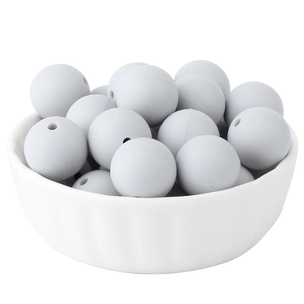 A white bowl filled with small, smooth, round silicone beads for jewelry making.