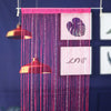 A pink beaded string curtain hangs against a dark blue background, featuring a heart-shaped design and the word LIVE.