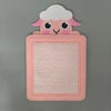 A pink felt board featuring a cute white fluffy animal face with pink ears and eyes.