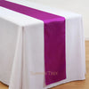 Elegant satin table runner in purple and white on a draped table.