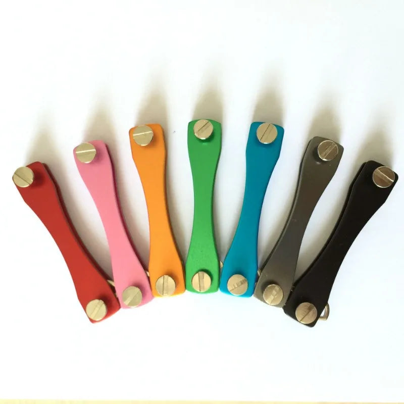 A row of aluminum key clips in various colors, including orange, pink, green, and blue, arranged horizontally.
