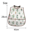 A white baby feeding bib with a cactus pattern and a catch pocket, shown flat.