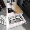 A kitchen counter featuring a stainless steel double sink and a wooden cutting board on a pink marble surface.