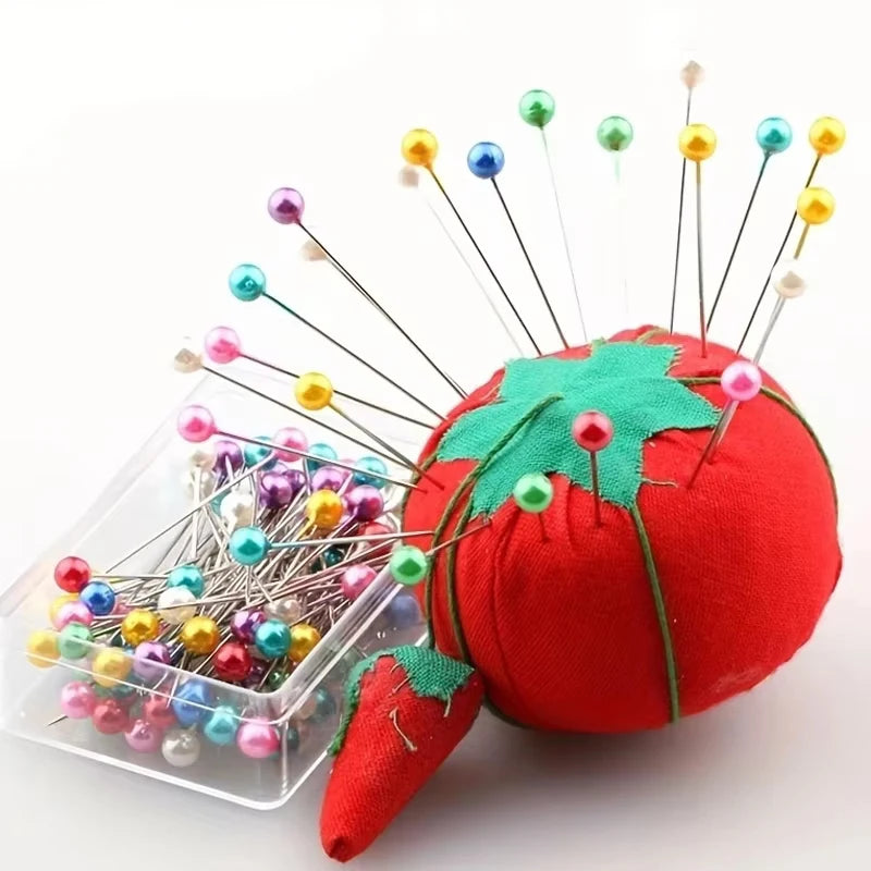 A red fabric ball head decorated with various colored pearlized ball pins sticking out.