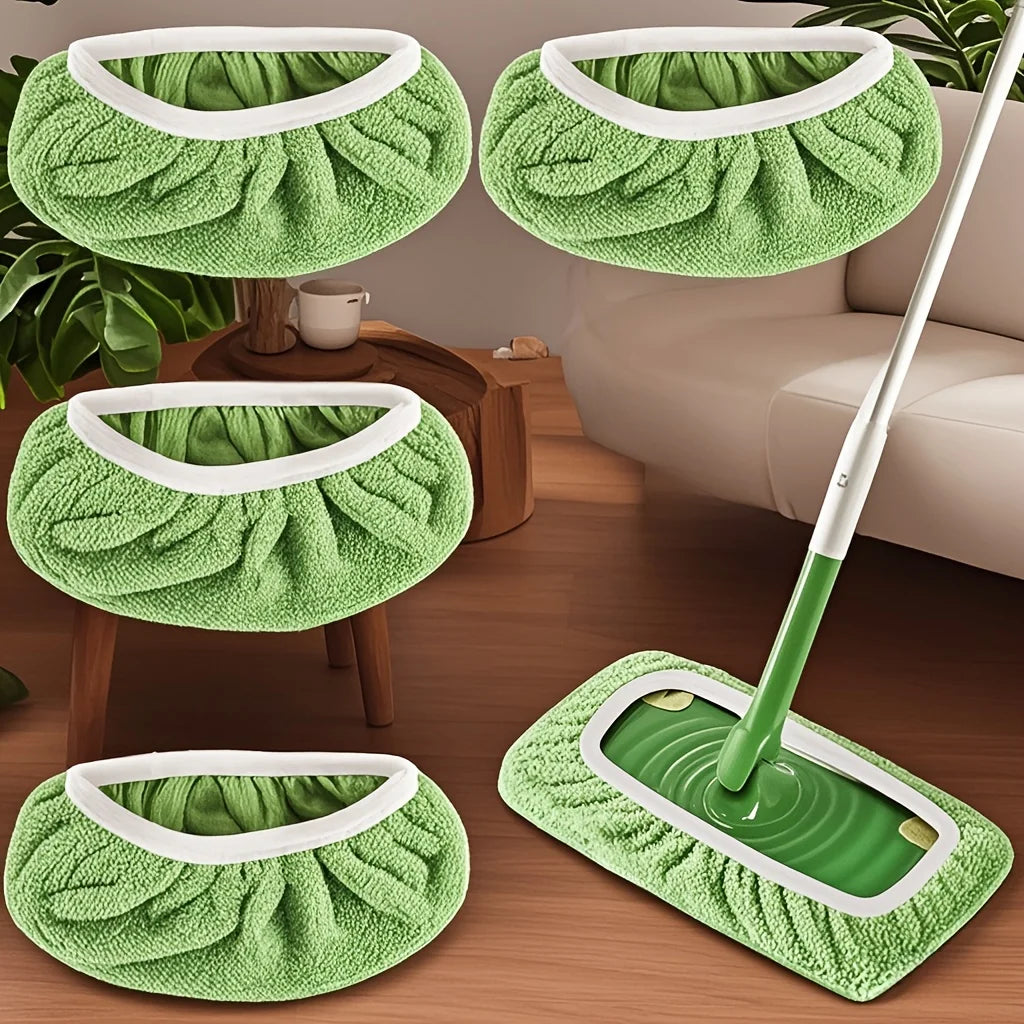 Set wiederverwendbare grüne Mikrofasertücher und ein Wischmopp mit weißen Griffen auf einem Holzfußboden.