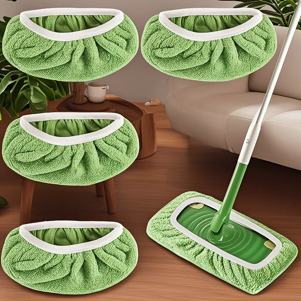 Set wiederverwendbare grüne Mikrofasertücher und ein Wischmopp mit weißen Griffen auf einem Holzfußboden.