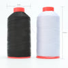 A spool of black heavy-duty nylon bonded thread with a red base, next to a spool of white thread.