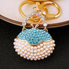 Gold-toned handbag keychain featuring blue crystal rhinestones and a pearl border.