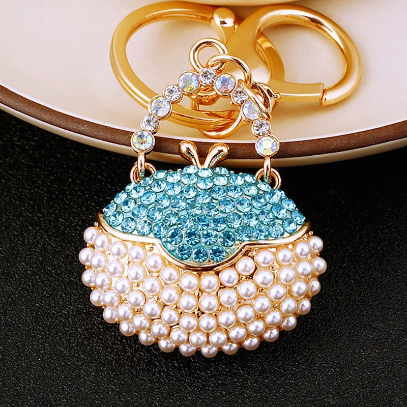 Gold-toned handbag keychain featuring blue crystal rhinestones and a pearl border.