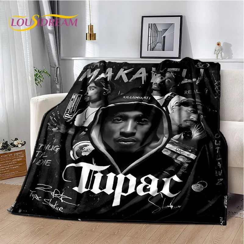 A black throw blanket featuring portraits of Eminem and Tupac with text on the fabric.