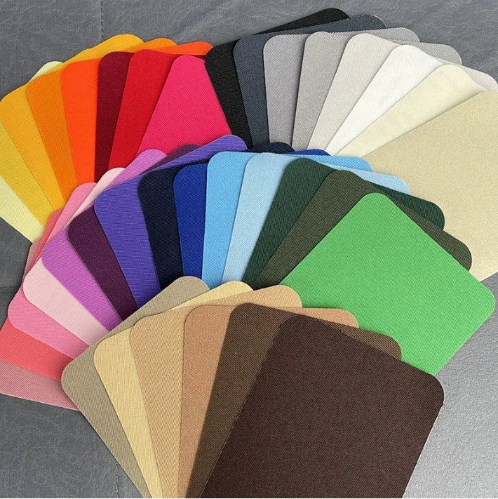 A colorful fan of iron-on fabric patches in various shades of pink, purple, green, yellow, and beige.