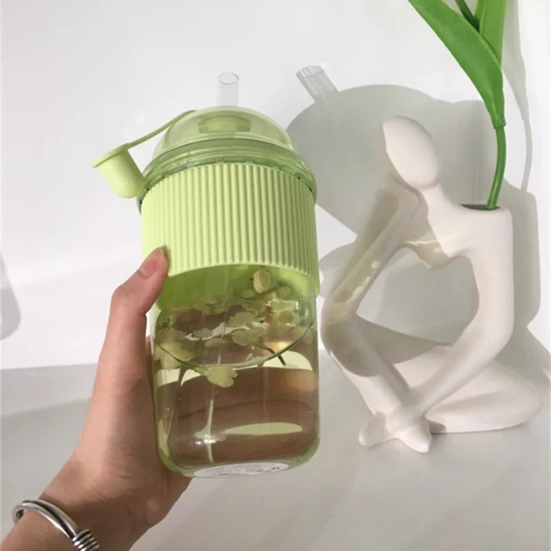 Eine Hand hält ein hellgrünes Glas mit passender Deckel und Strohhalm vor weißem Hintergrund.
