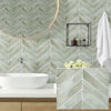 A modern bathroom featuring a white vessel sink and a light green chevron patterned wall tile.