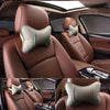 Close-up view of a brown leather car seat with a beige knitted neck pillow installed on the headrest.