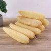 A stack of natural yellow loofah body scrubbers with hanging ropes resting on a wooden surface.