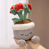 A cute artificial flower plush doll with red petals and green leaves is held in a hand.