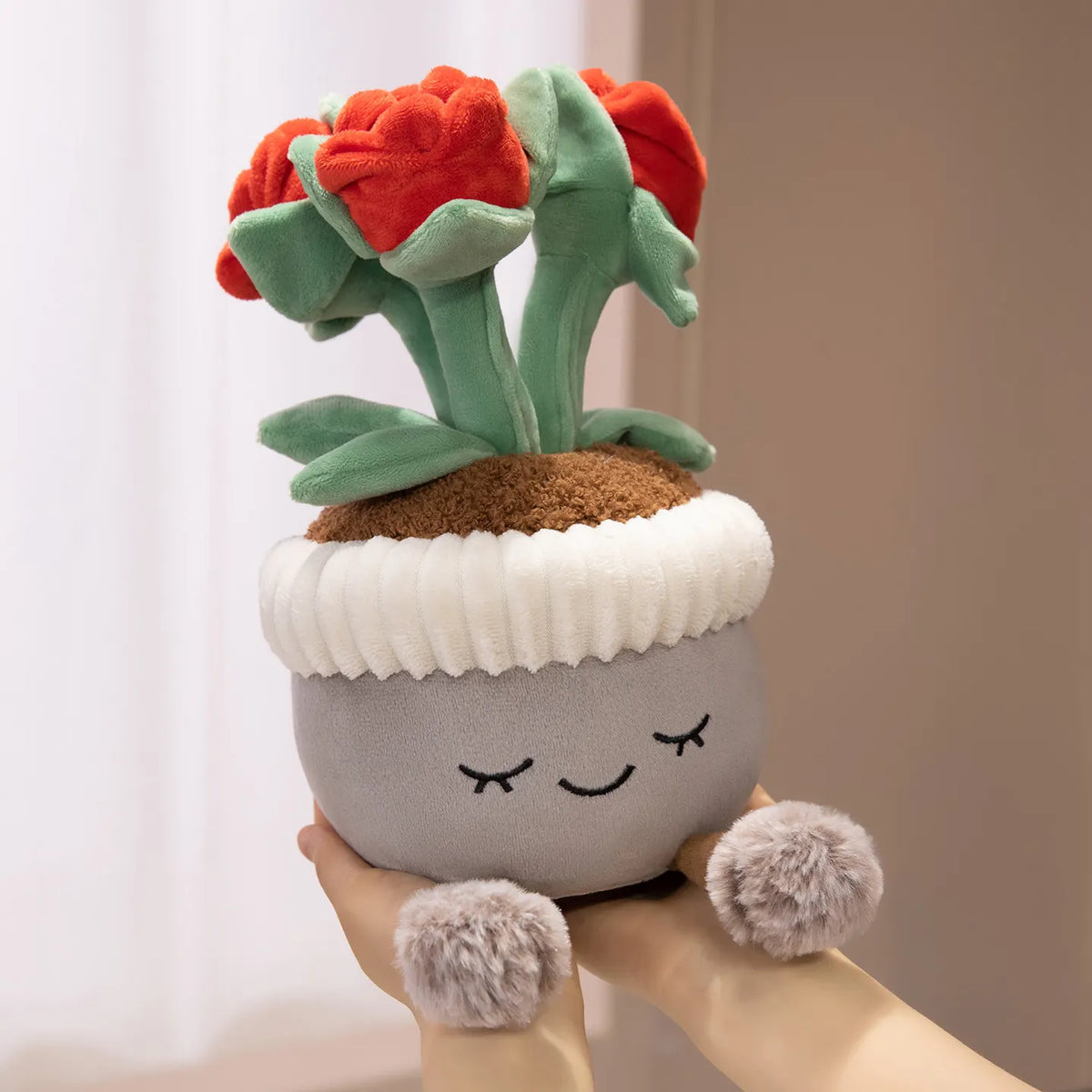 A cute artificial flower plush doll with red petals and green leaves is held in a hand.