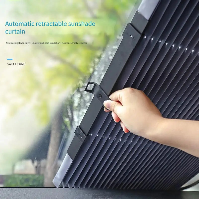 A hand is adjusting an automatic retractable sunshade curtain on a car windshield.